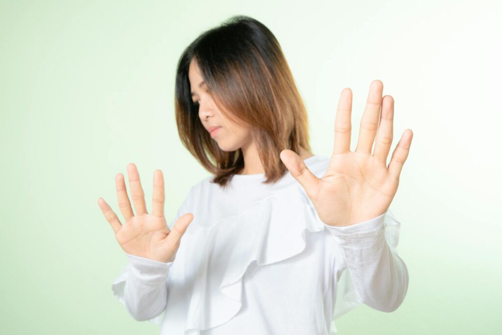 Studio shot of a woman raising hands in a stop gesture, expressing refusal or no.