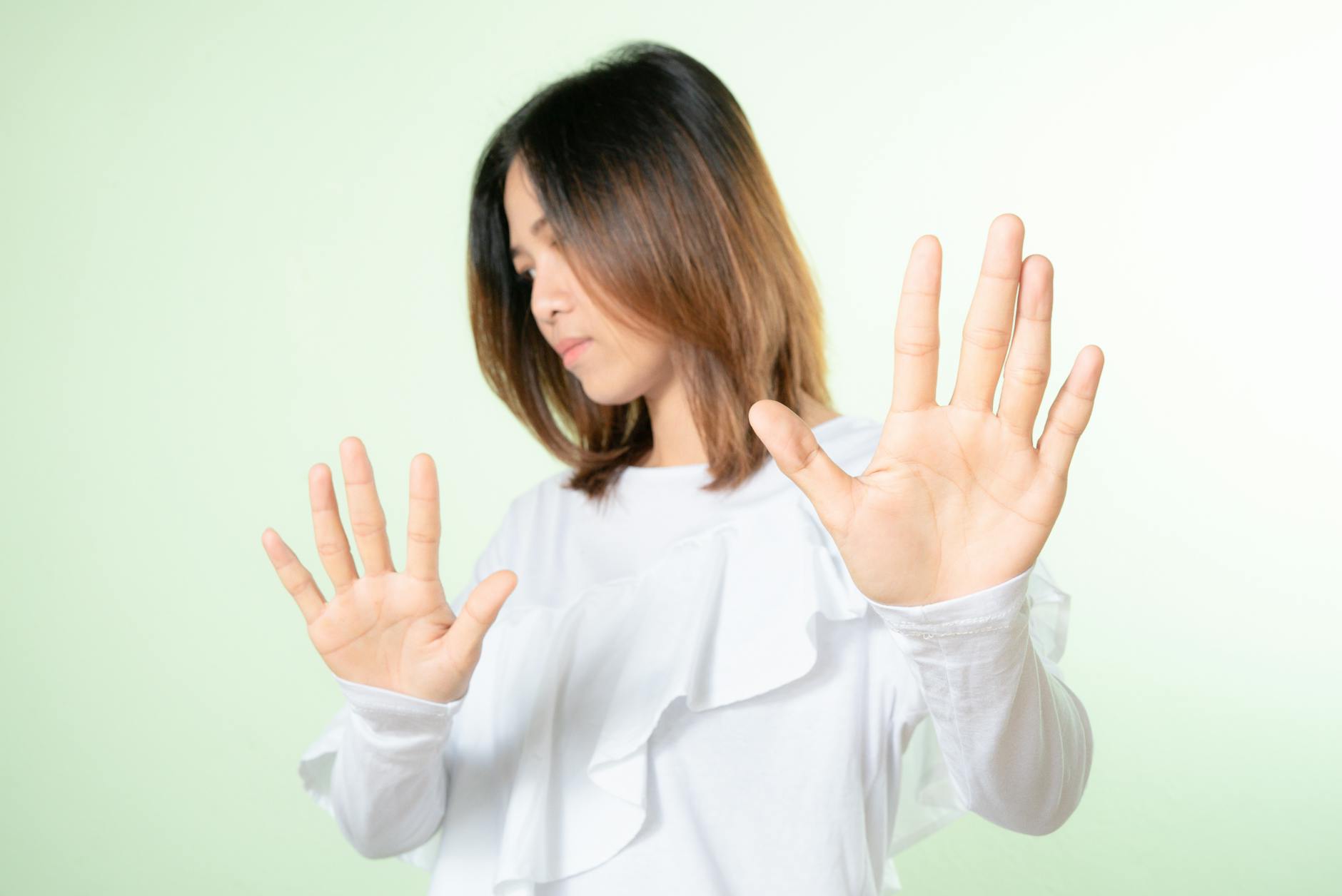 Studio shot of a woman raising hands in a stop gesture, expressing refusal or no.